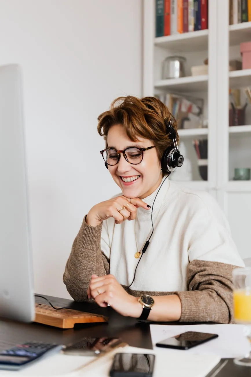 A woman sitting at a desk with a laptop and headphones on.